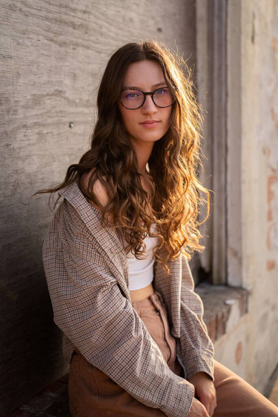 A vertical closeup of an attractive female with glasses standing near wall - Fotografie, Obrázek