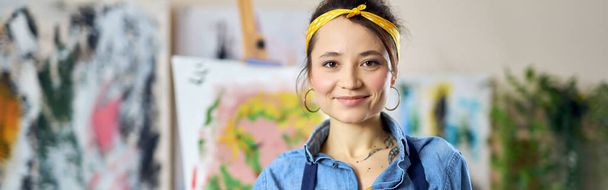 Pleased young woman, female artist in apron smiling at camera, posing with her hands in paint, standing at home studio workshop. Art, hobby, leisure concept - Photo, image