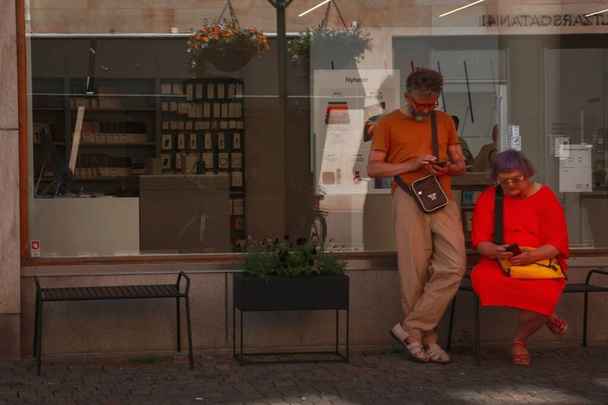 An elderly couple on the street looking at their phones - Fotoğraf, Görsel