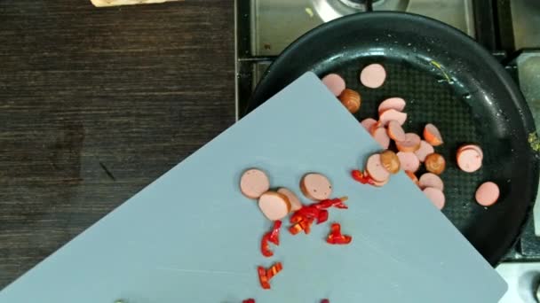 vista aérea de salchichas fritas con cebolla y pimiento rojo cocina doméstica - Imágenes, Vídeo