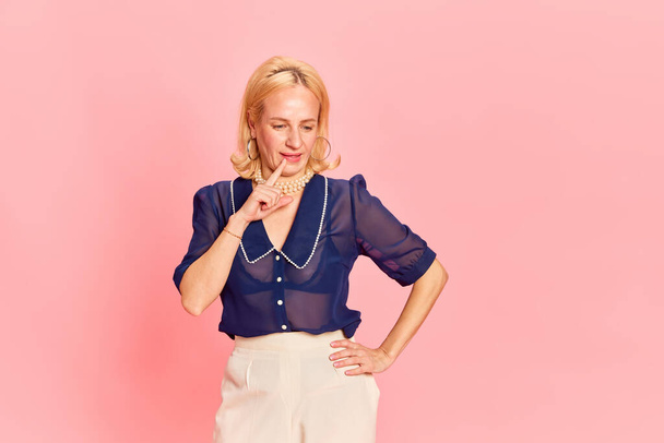 Creative. One attractive blond woman wearing fancy retro costume in process of creating good ideas over pink studio background. Concept of emotions, business, career, fashion, beauty, vintage, ad - Photo, Image