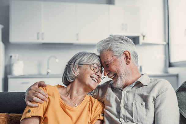 Счастливый зрелый муж и жена сидеть отдохнуть на диване дома обнимая и обнимая, показать любовь ухода, улыбаясь старшая любящая пара расслабиться на диване весело, наслаждаться нежной романтической семьи выходные вместе
 - Фото, изображение