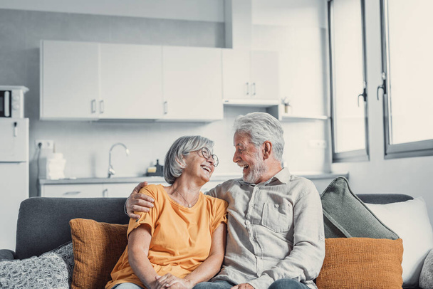 Glücklich reife Eheleute sitzen auf der Couch zu Hause kuscheln und kuscheln, Pflege Zuneigung zeigen, lächelnde Senioren liebende Paare entspannen auf dem Sofa Spaß haben, genießen zarte romantische Familienwochenende zusammen - Foto, Bild