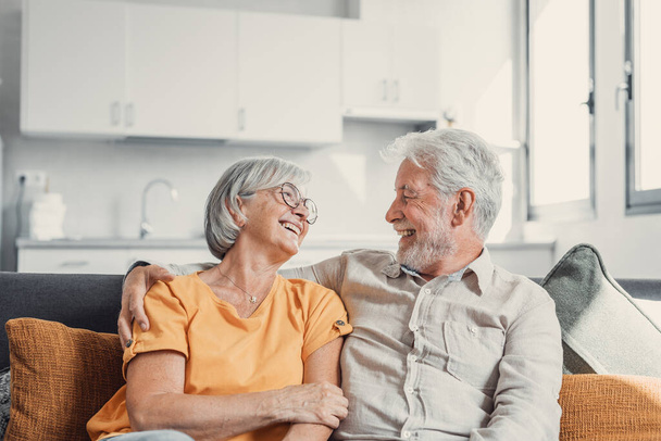 Happy laughing older married couple talking, laughing, standing in home interior together, hugging with love, enjoying close relationships, trust, support, care, feeling joy, tenderness - Photo, Image