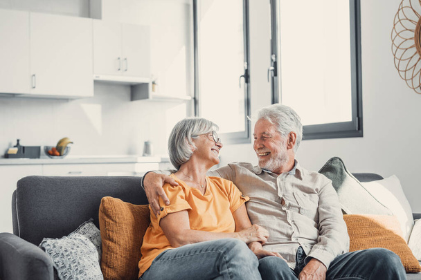 Happy laughing older married couple talking, laughing, standing in home interior together, hugging with love, enjoying close relationships, trust, support, care, feeling joy, tenderness - 写真・画像