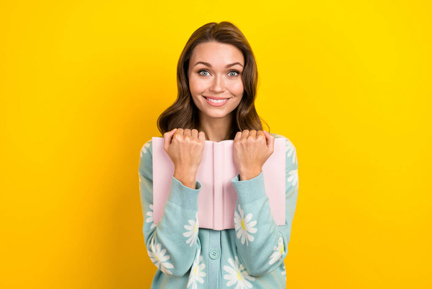 Portrait of lovely positive girl beaming smile arms hold book isolated on yellow color background. - Foto, Imagen
