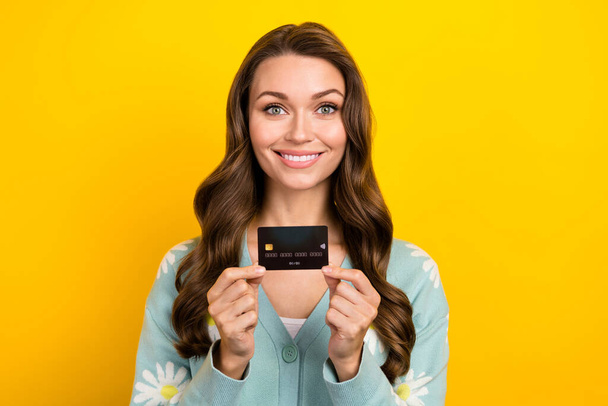 Photo advert of young cheerful lady promoter hold black premium plastic card demonstrate wireless nfc option isolated on yellow color background. - Fotografie, Obrázek