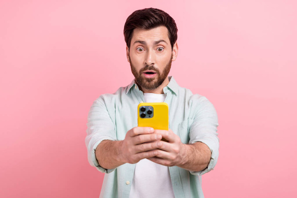 Photo of young impressed reaction funny man hold phone recording video his grimace face wear trendy shirt isolated on pink color background. - Фото, зображення