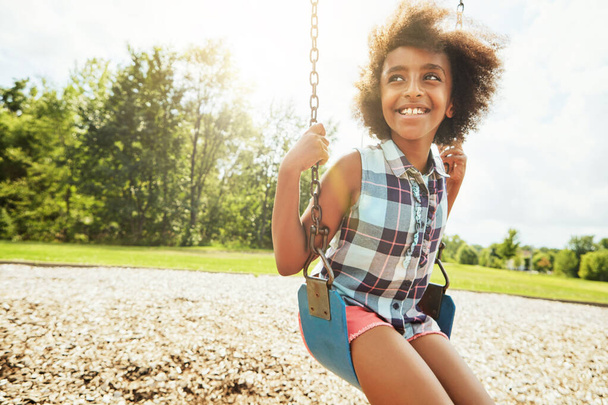 Быть молодым означает иметь только дни веселья. молодая девушка играла на качелях в парке - Фото, изображение