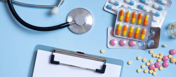 Banner met tablet, kleurrijke pillen en stethoscoop platte lay, bovenaanzicht. Begrip gezondheidszorg en geneeskunde. - Foto, afbeelding