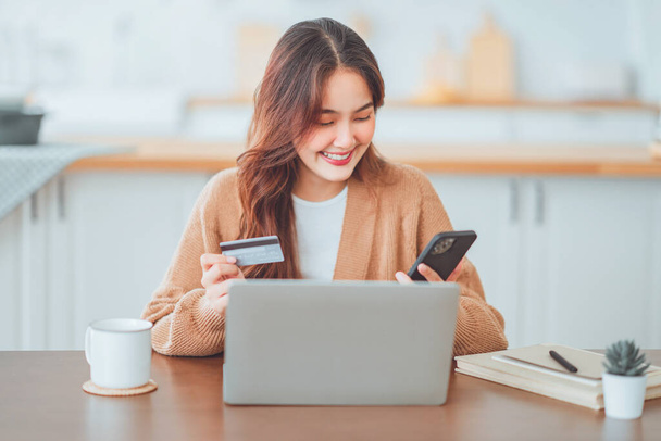 Online fizetés, Boldog ázsiai nő kezében egy hitelkártya és használata okos telefon és laptop az online vásárlás - Fotó, kép