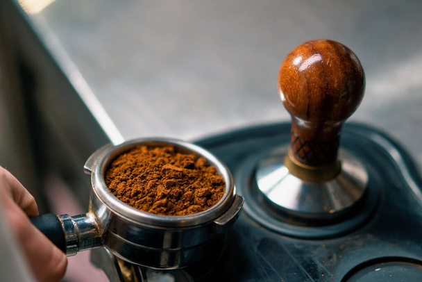 A professional barista in coffee shop prepares ground coffee by tamping fresh ground coffee beans close-up - Foto, Imagem