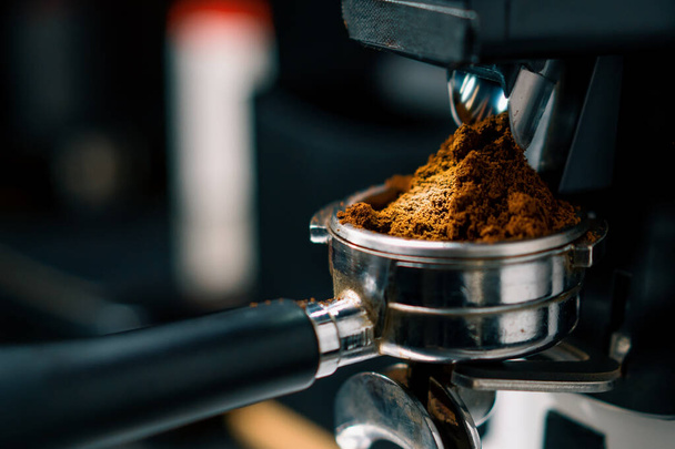 La macchina professionale del macinino di uso del lavoratore barista per macinare i chicchi di caffè freschi per fare la caffetteria calda della bevanda - Foto, immagini