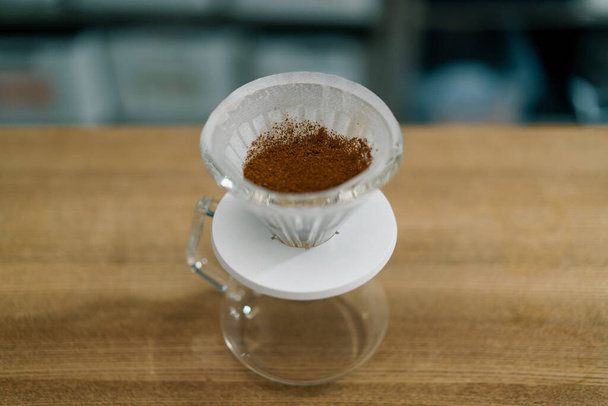 Η διαδικασία παρασκευής καφέ φίλτρου με τη χύτευση ζεστού νερού πάνω από στρώμα αλεσμένου καφέ στο φίλτρο - Φωτογραφία, εικόνα