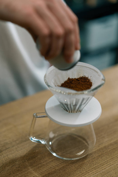 The process of making filter coffee by pouring hot water over layer of ground coffee on the filter - 写真・画像