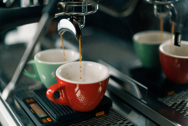 Het gieten van koffie stroomt uit de machine in de beker het maken van warme drank met behulp van filterhouder vers gemalen koffie stromen - Foto, afbeelding