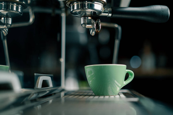 Nalévání kávy proudí ze stroje do šálku, takže horký nápoj pomocí filtru držák čerstvě mletá káva teče - Fotografie, Obrázek