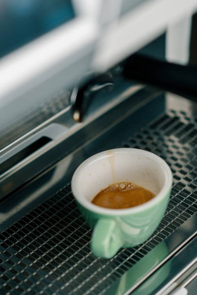 Выливание кофе течет из машины в чашку делает горячий напиток с помощью фильтр держатель свежемолотый кофе потоки - Фото, изображение