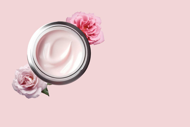 Facial cream in a glass jar with powdery rose flowers on a light pink background. Cosmetics with hyaluronic acid. Natural branding skin care product. Flat lay, top view, copy space. - Foto, afbeelding