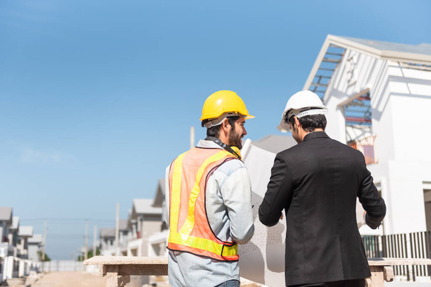 建設現場のチームワークマン、工場に立っている間に働くデジタルタブレットと青写真を使用して安全ヘルメットハード帽子の2人の土木技術者. - 写真・画像