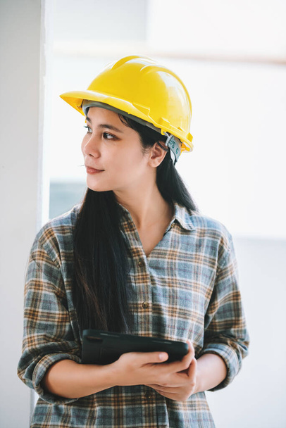 Portrét asijské ženy stavební dělnice držící digitální tablet pro práci na staveništi, nošení hardhat a bezpečnostní vybavení pro bezpečné. - Fotografie, Obrázek