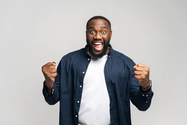 Yes. Extremely satisfied African-American man celebrating his victory rejoicing and showing yes gesture, positive emotions. Indoor studio shot isolated on white background - Foto, Bild