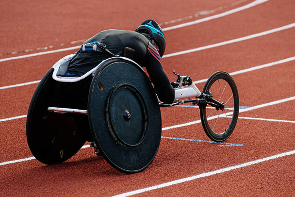 rear view para athlete in wheelchair racing riding on red track stadium, summer para athletics championships - Photo, Image