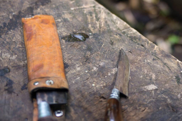 A closeup of a knife with a leather sheath on a grungy surface. - Φωτογραφία, εικόνα