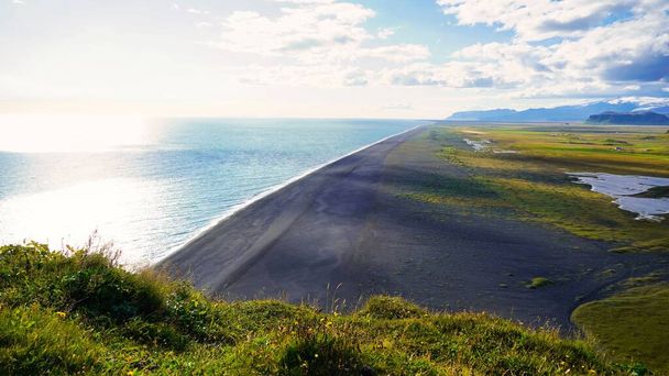 A view of the greenery along the coastline on a sunny day in Iceland - 写真・画像