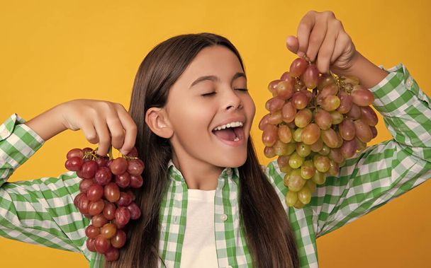 happy teen girl with grapes bunch on yellow background. - Fotoğraf, Görsel