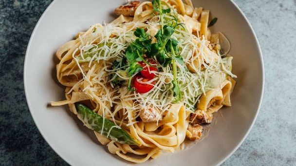 of delicious pasta topped with basil, cheese and tomato - 写真・画像