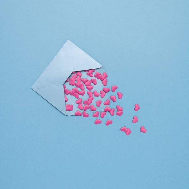 A love letter with pink paper hearts on the blue background with copy space - Valentine's day greeting card design - Foto, afbeelding
