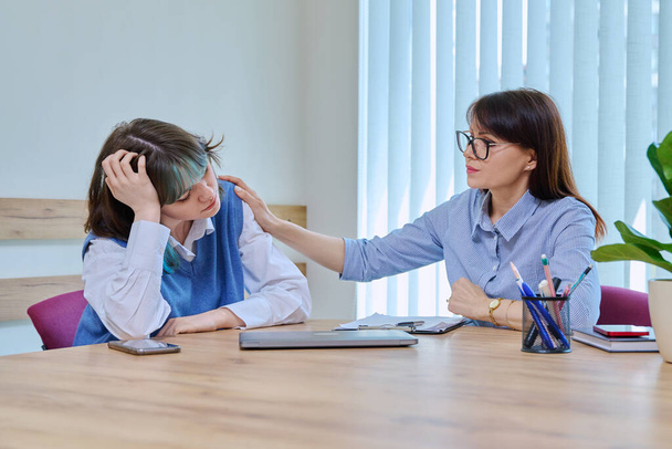 Unhappy upset sad girl student teenager at meeting with therapist, counselor, mental health specialist, during therapy in office of college psychologist. Social life, psychology, youth concept - 写真・画像