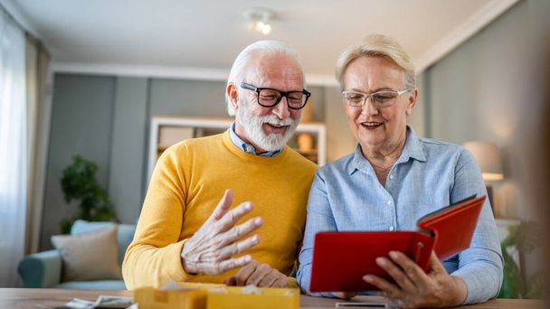 Starsza para mężczyzna i kobieta mąż żona patrząc zdjęcia rodzinne album kaukaski stary mężczyzna i kobieta dziadek i babcia szczęśliwy uśmiech w domu ze starymi zdjęciami prawdziwe ludzie kopiować przestrzeń - Zdjęcie, obraz