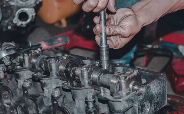 A close-up shot of hands repairing a metallic engine - Foto, imagen
