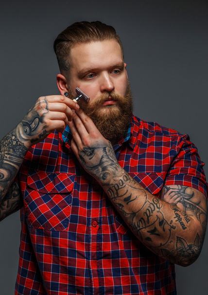 Brutal tattooed male shawing his beard - Photo, Image