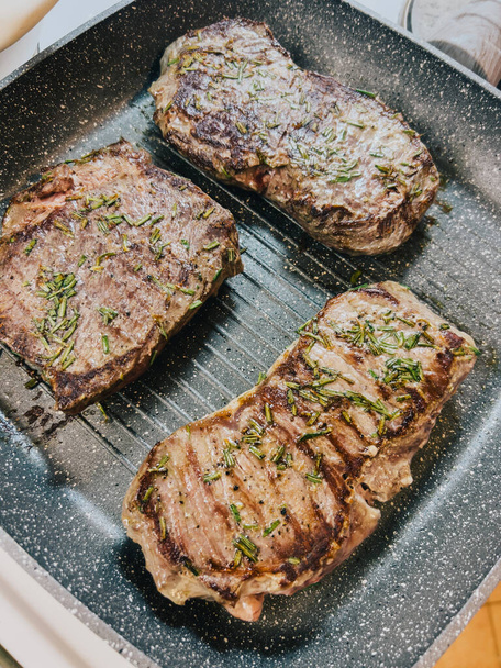 Pieces of meat with rosemary are fried in a grill pan. High quality photo - Photo, Image