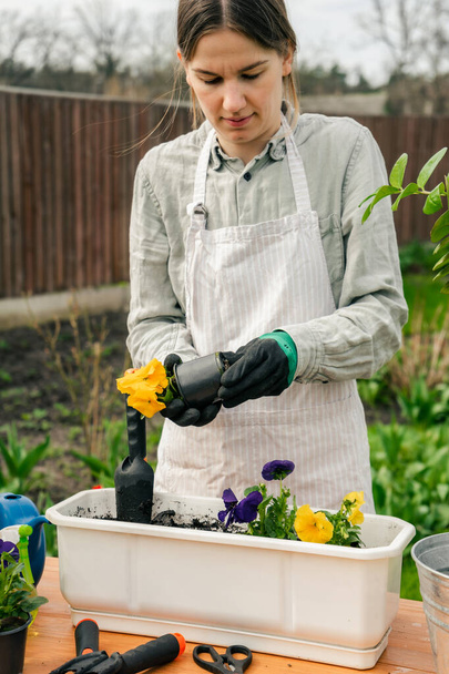 une jolie femme caucasienne travaillant dans le jardin plantant les fleurs dans des pots - Photo, image