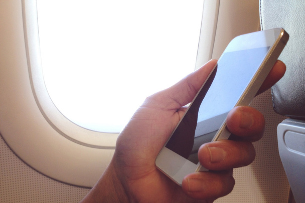 Hombre de negocios se sienta en el avión mirando su teléfono celular
 - Foto, Imagen