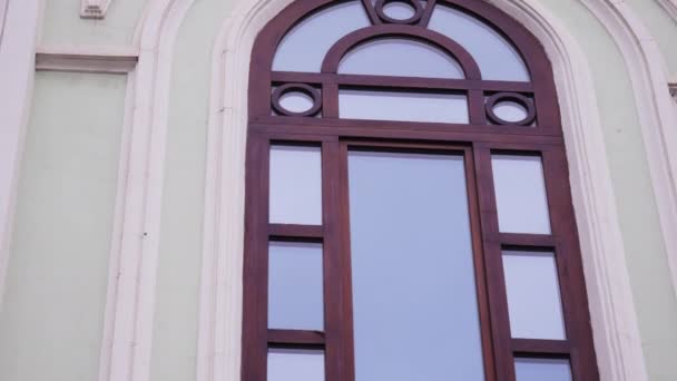 Fasada starego budynku z wysokim oknem łukowym i rzeźbionymi elementami. Materiał filmowy. Pojęcie architektury - Materiał filmowy, wideo