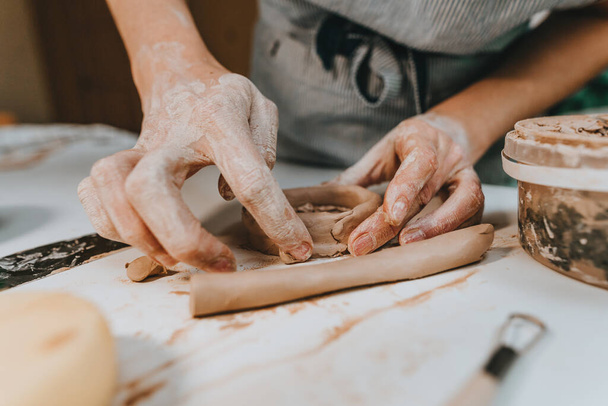 Zbliżenie żeńskich rąk pracujących z gliną robiących filiżankę w warsztacie. Skupienie selektywne. - Zdjęcie, obraz