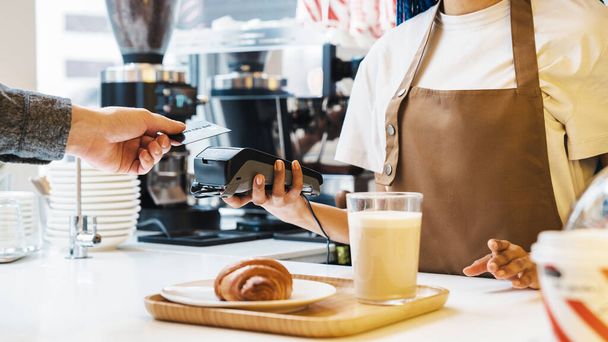 Cropped photo of customer using credit card for payment. Waiter holding credit card machine in cafe. Electronic money. Mobile banking - Photo, Image