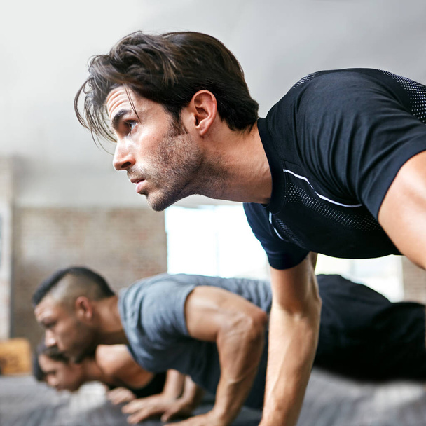 A test és az elme ereje. Egy csapat ember fekvőtámaszt csinál egy edzőteremben. - Fotó, kép