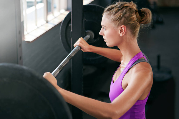 Bueno, no se va a levantar solo. una joven haciendo ejercicio con pesas en el gimnasio - Foto, imagen