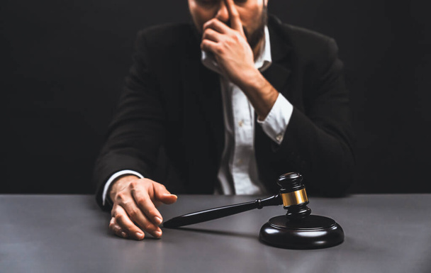 Focus gavel with blur lawyer sitting at his desk with worried and exhausted expression, feeling weight of pressure and stress of making hard decision on verdict with gavel hammer in hand. equility - Valokuva, kuva
