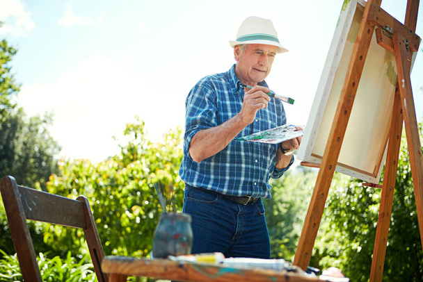 Painting makes him feel alive. a senior man painting in the park - Foto, imagen