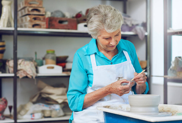 Ihren Ruhestand im Atelier verbringen. Eine Seniorin stellt in einer Werkstatt einen Keramiktopf her - Foto, Bild