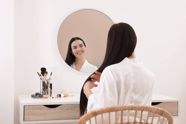 Beautiful young woman at dressing table indoors - Photo, image
