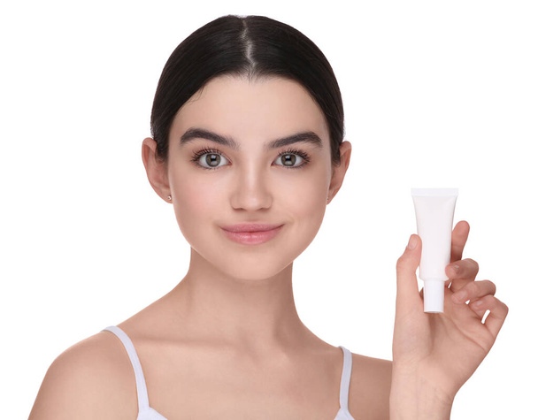 Teenage girl holding tube of foundation on white background - Фото, изображение