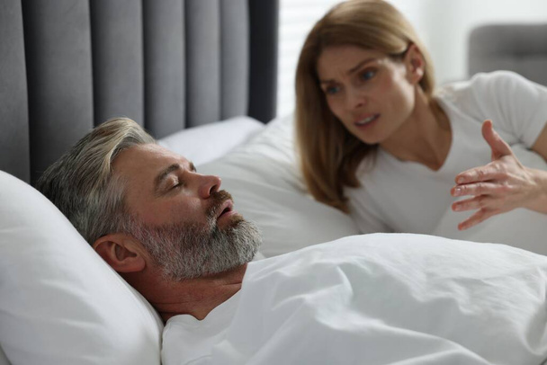 Irritated woman near her snoring husband in bed at home - Фото, зображення